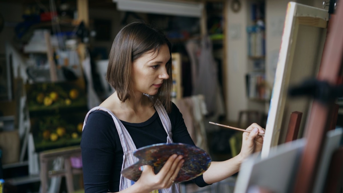 A person painting carefully at an easel